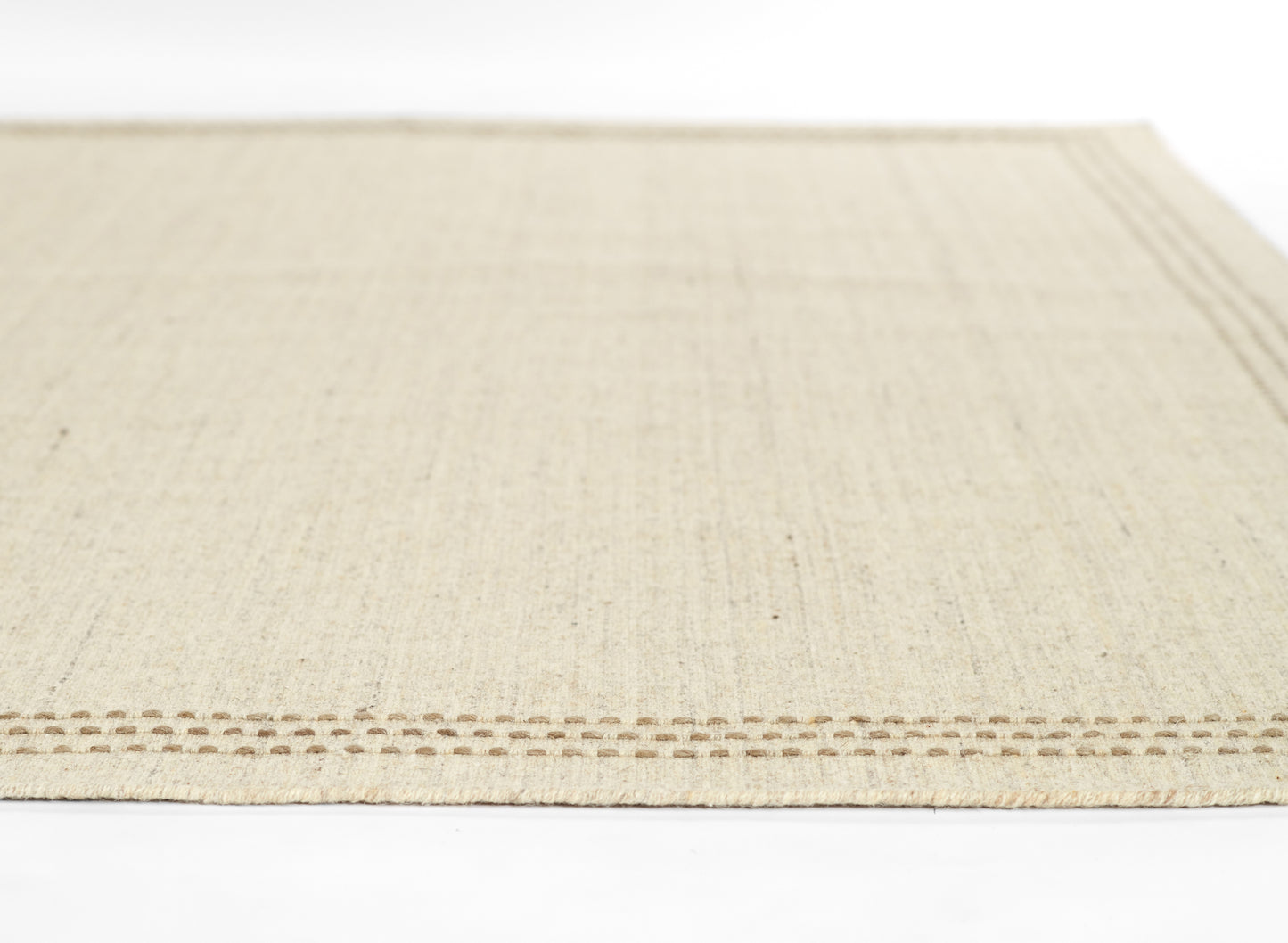 Natural beige woven rug with subtle vertical fibers and brown stitched dotted border along the edge.