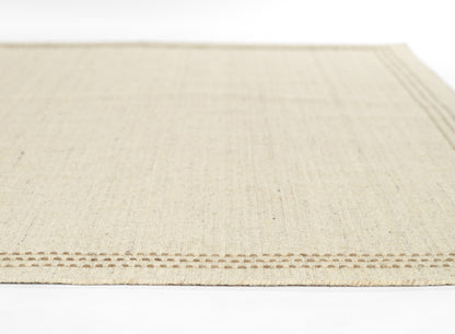 Beige natural-fiber rug with a subtle woven texture and a brown stitched border edge.