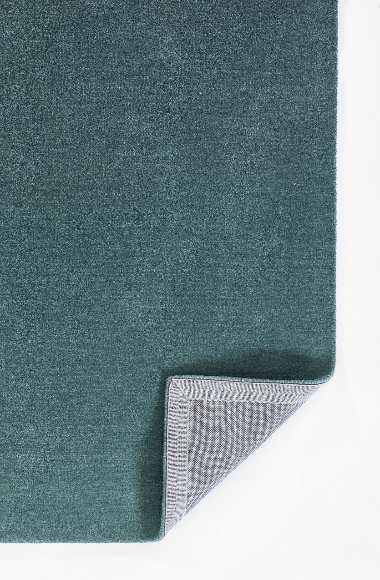 Teal blue rug with soft texture, folded corner revealing light grey backing.
