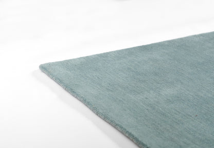 Teal blue ombre rug with soft plush pile and finished edge, angled view.