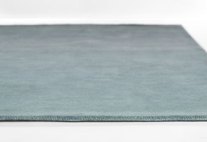 Ombre blue rug with teal-to-navy gradient, low-pile fabric and fringe edge for living room decor.
