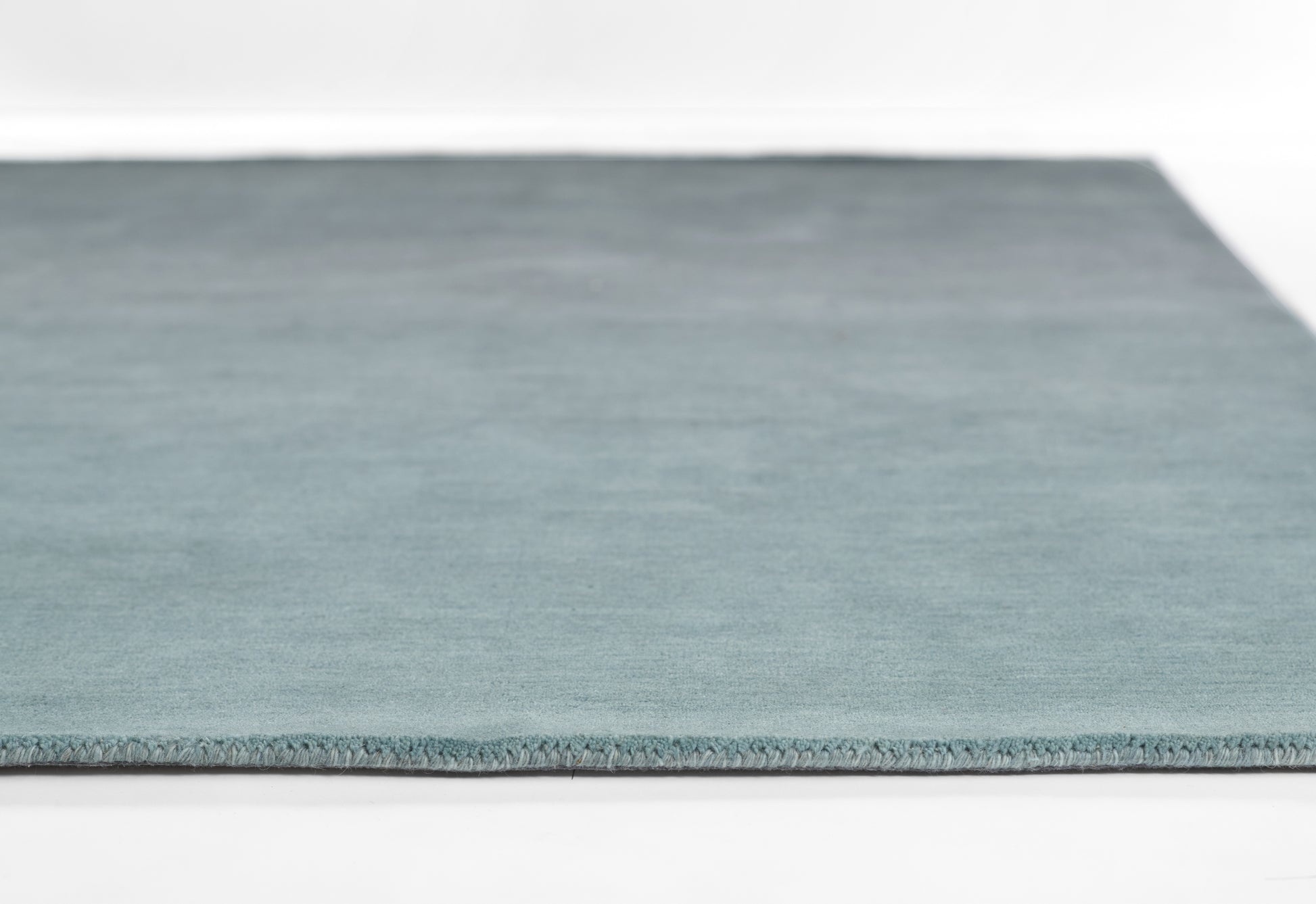 Blue ombre rug in teal gradient with fringed edge.