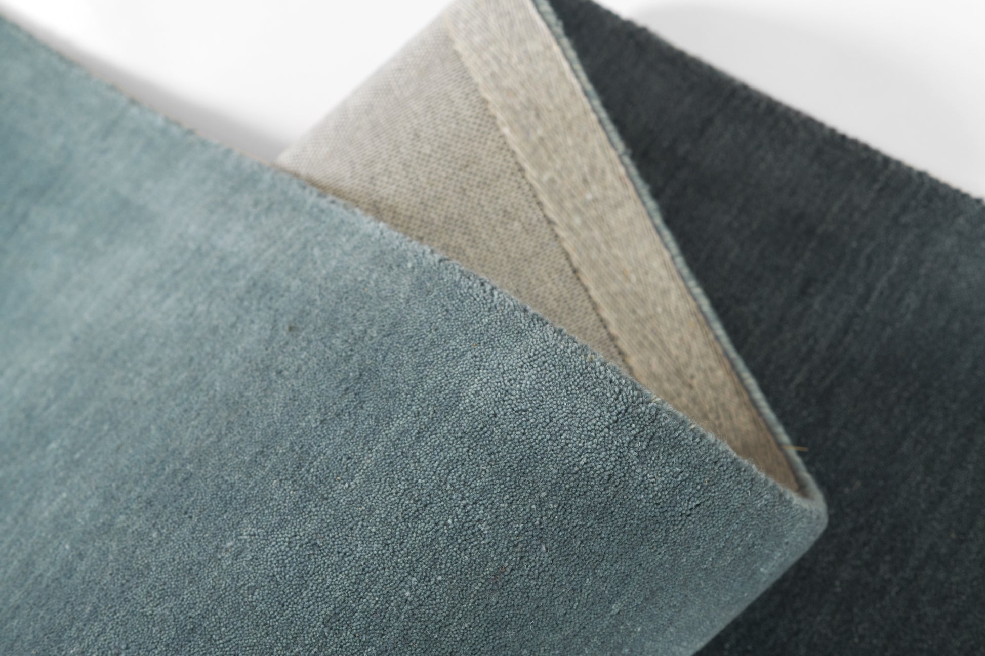 Blue ombre velvet cushion with beige underside, textured fabric and folded edge detail.