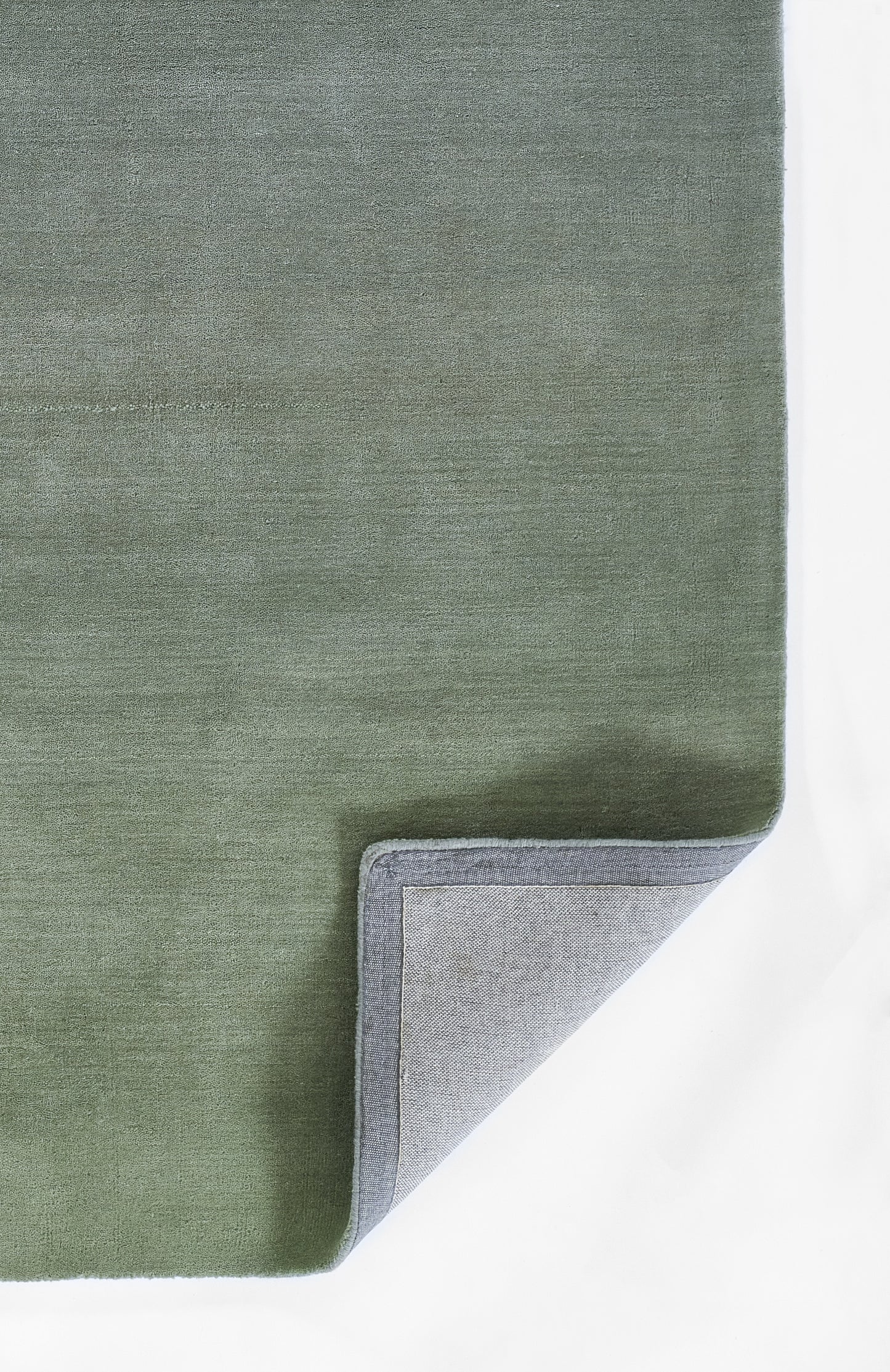 Rectangular green ombre rug with soft velvet texture; folded corner reveals light gray backing.
