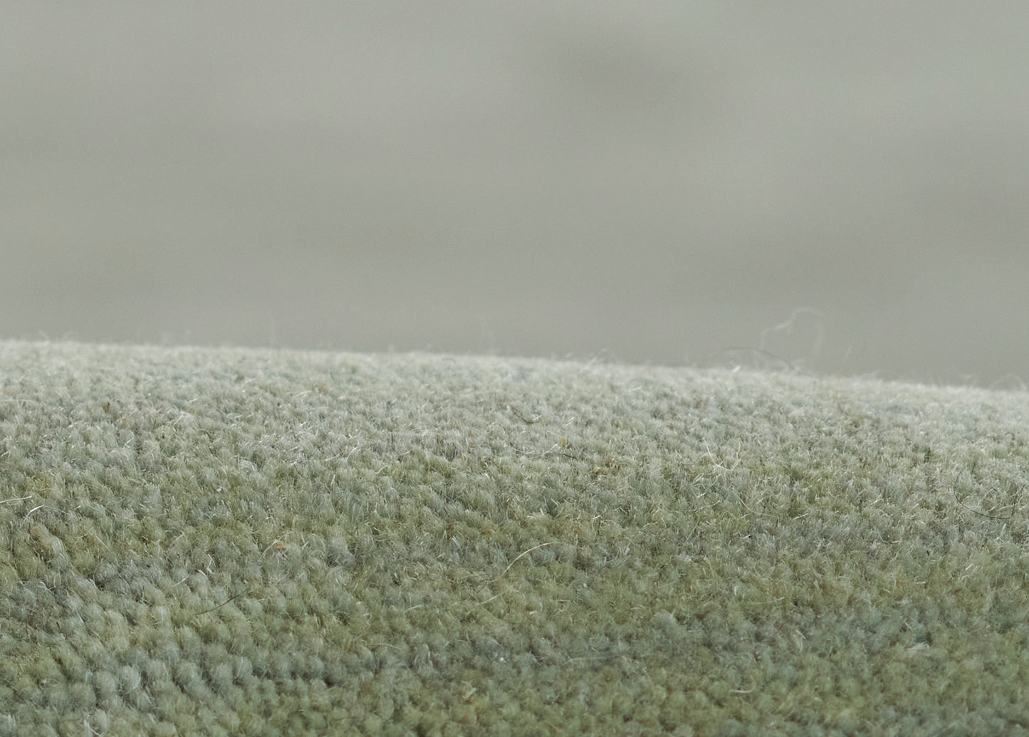 Close-up of olive-green ombre rug with dense plush pile and soft texture.