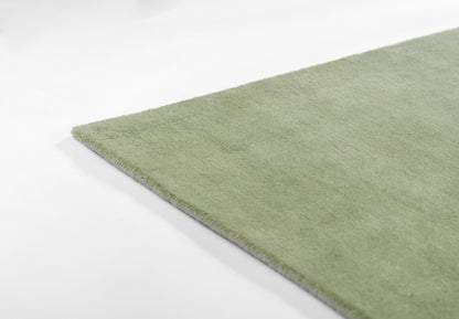 Light green ombre rug with soft plush pile and straight edge, close-up corner.