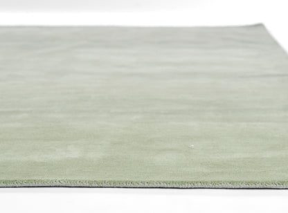 Rectangular sage-green ombre rug with soft low pile and fringe edge