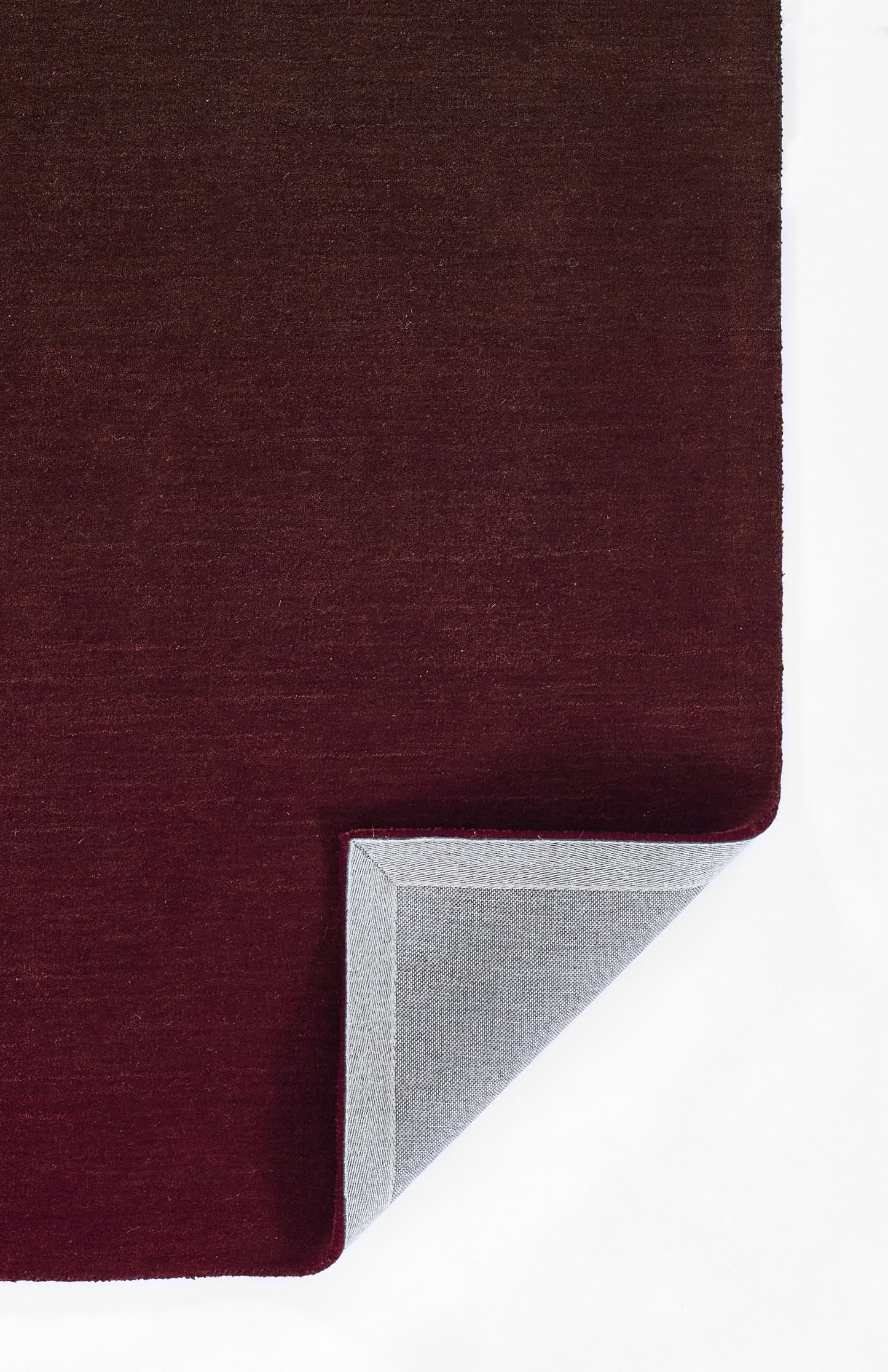 Dark burgundy ombre rug with soft velvet pile; corner folded to reveal light gray underside.