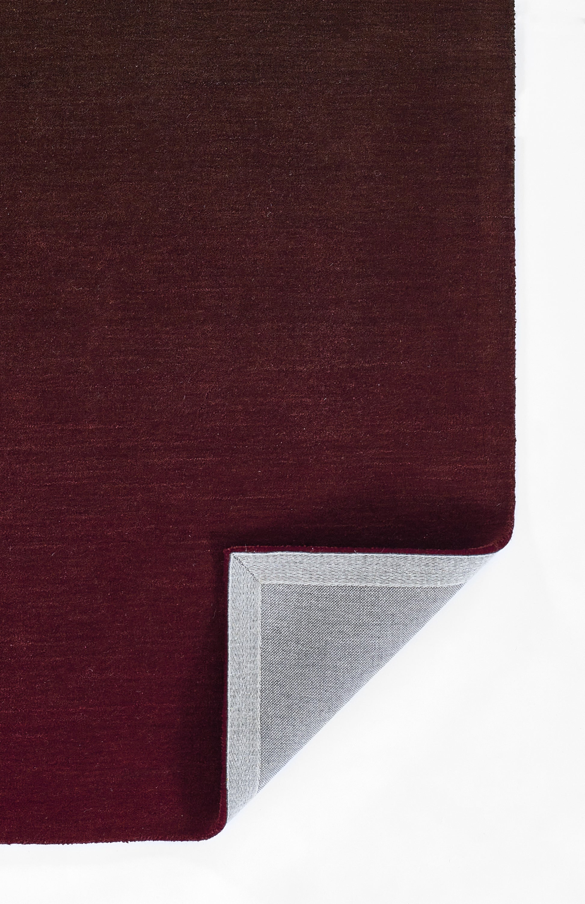 Dark burgundy ombre rug with soft velvet pile; corner folded to reveal light gray underside.