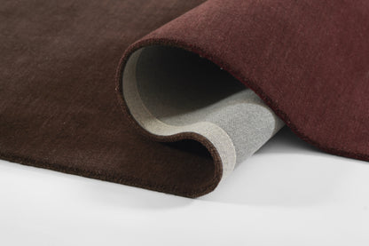 Ombre burgundy rug rolled to expose gray backing; plush, soft surface with rich color.