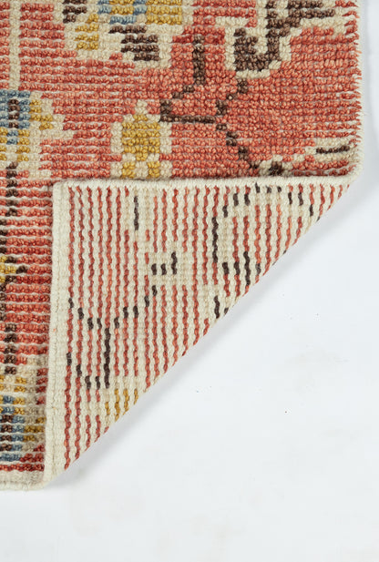 Red oriental rug with floral motifs, cream and blue accents, folded corner reveals striped underside.