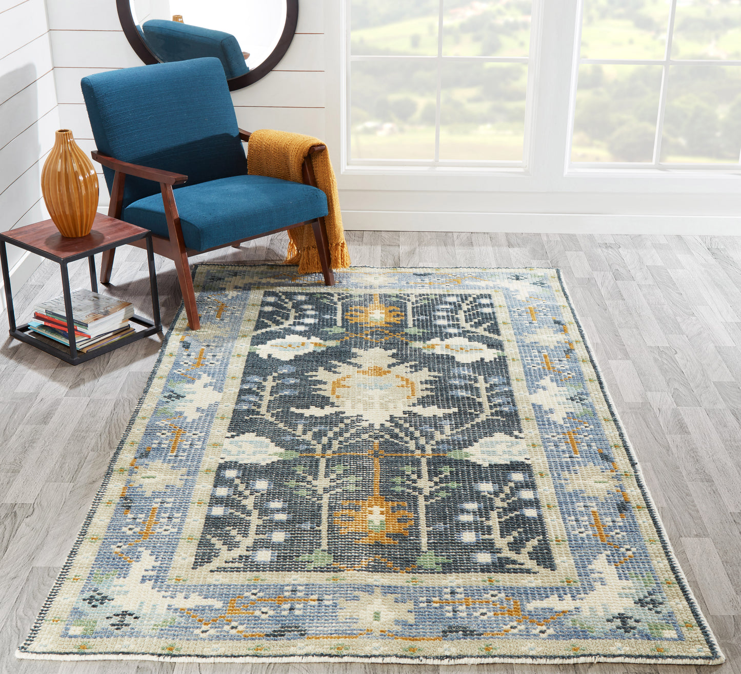 Rectangular woven rug in blue, teal, ivory and orange with a floral medallion and a Persian-style border.