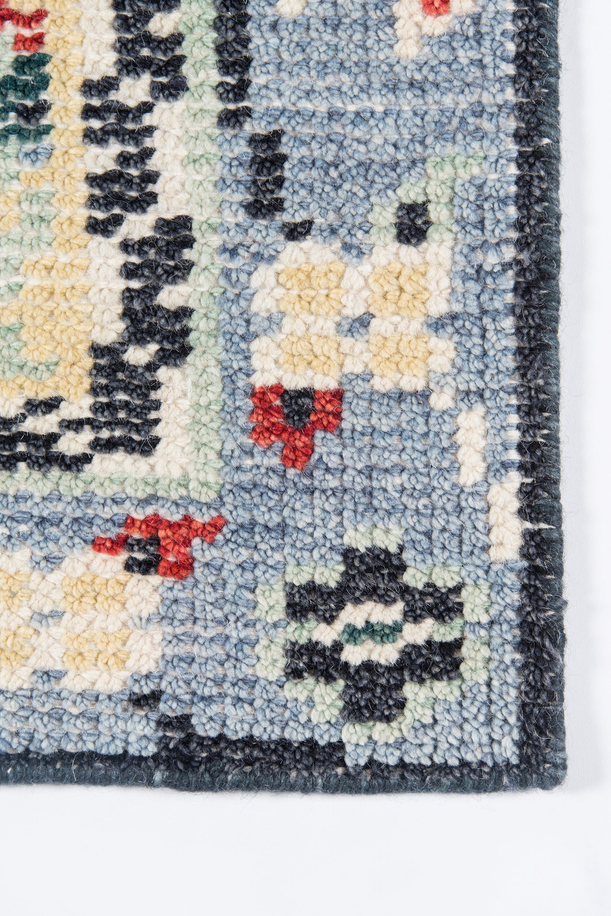 Close-up of a blue oriental tufted area rug with cream, red and black floral motifs; dark border.