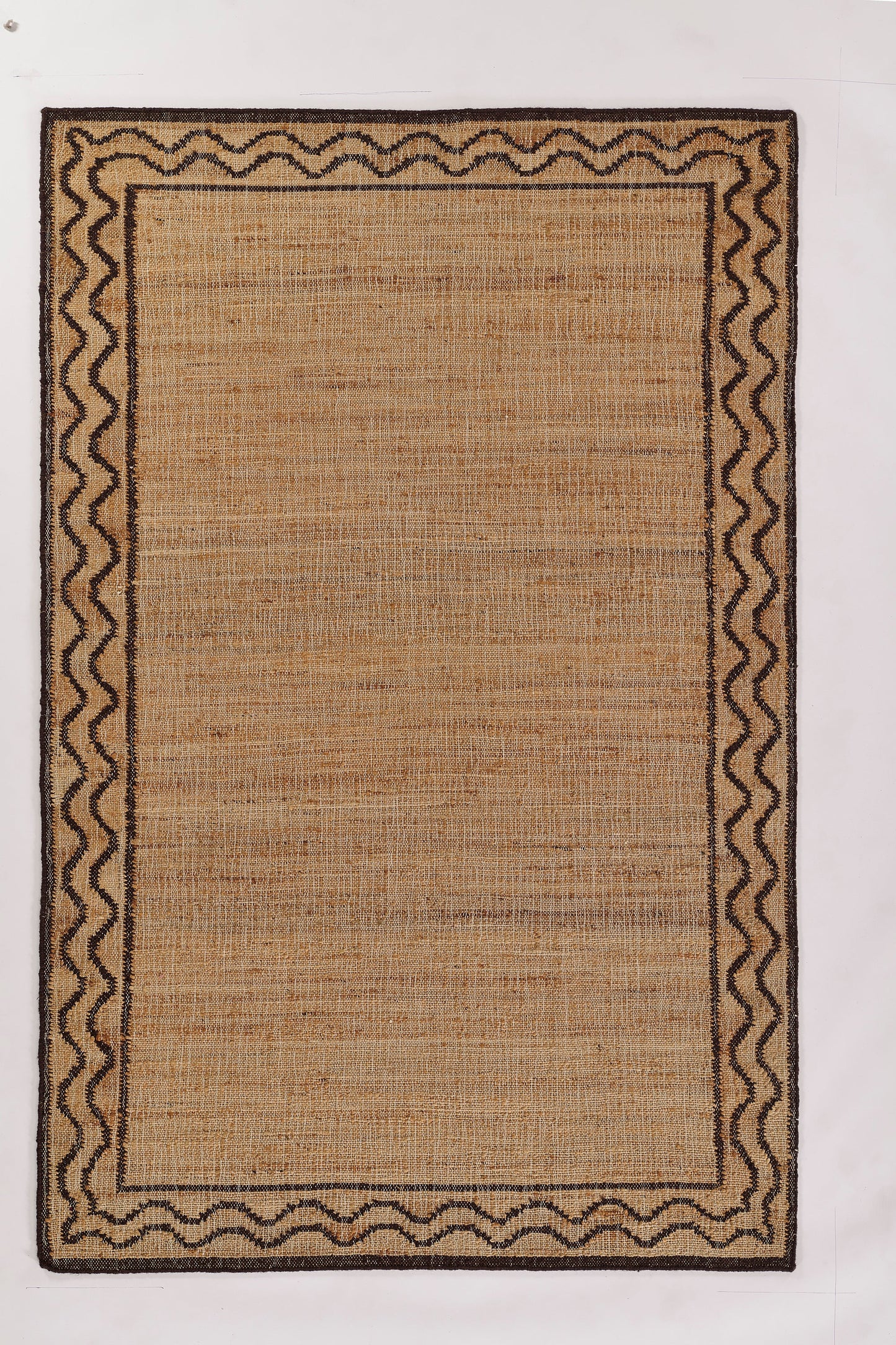 Rectangular natural jute rug with dark brown zigzag border and inner frame; rustic woven beige center.