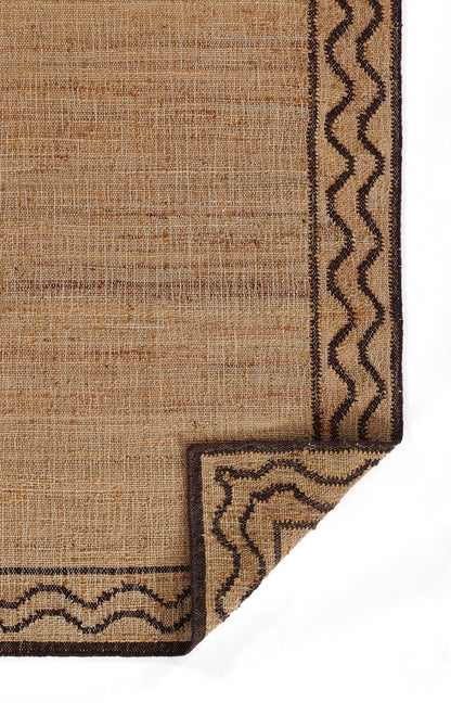 Natural beige woven rug with dark brown wavy border and folded corner detail.