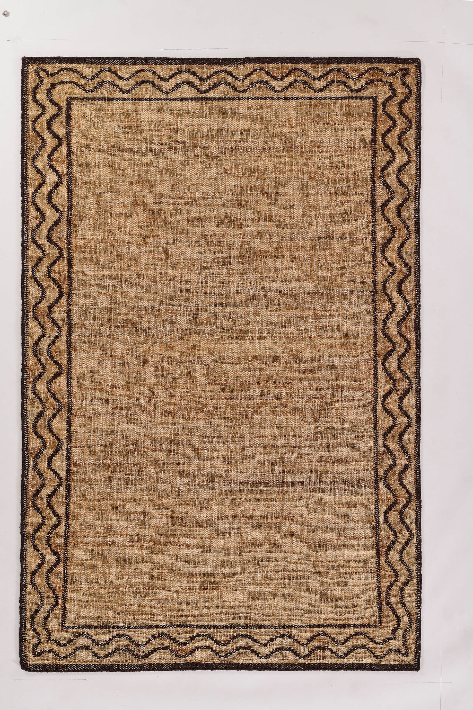 Rectangular natural jute rug with tan center and dark brown wavy border; rustic, boho area rug for living room or entryway.