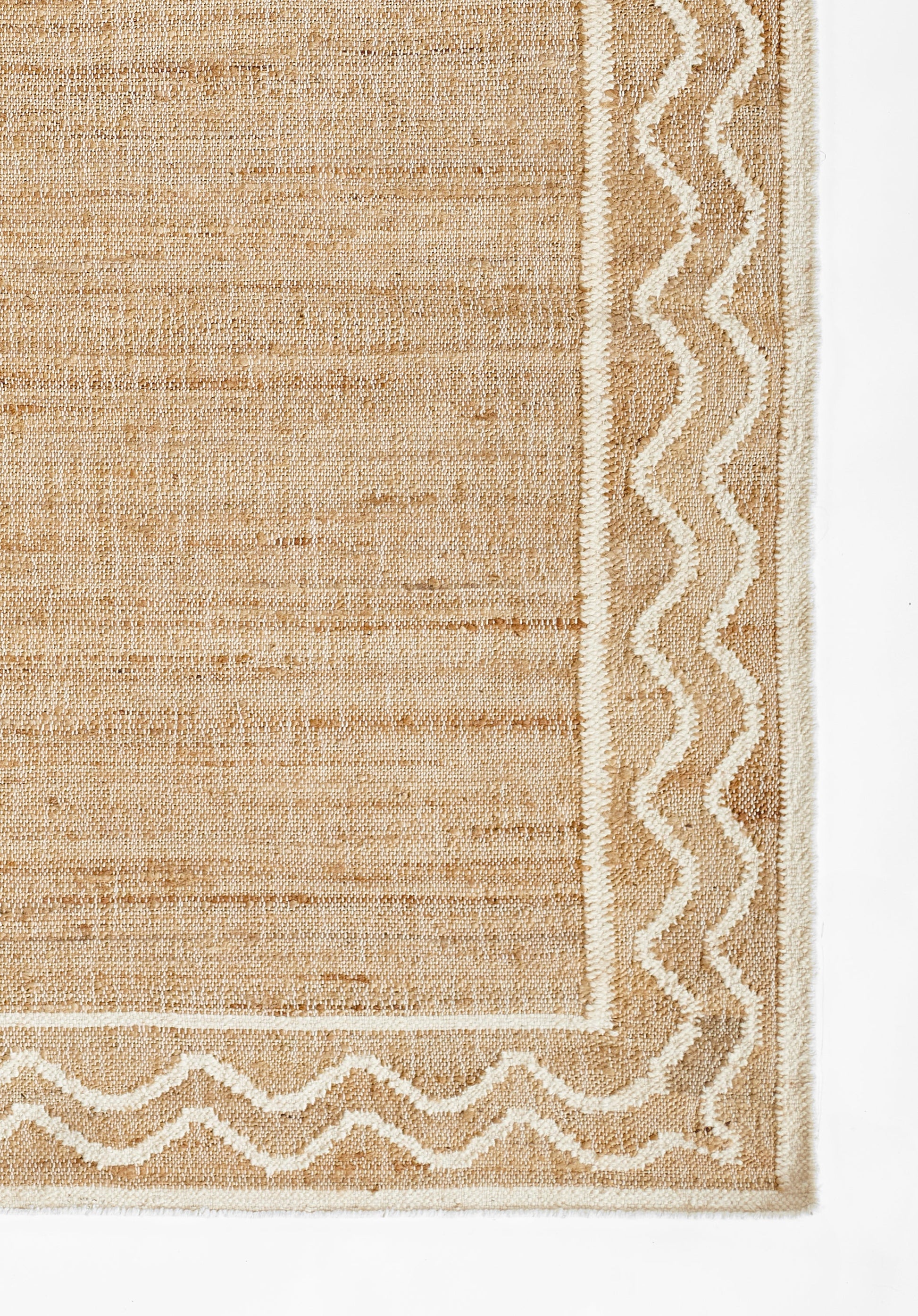 Natural beige woven rug with a white zigzag border and textured, coarse fiber surface.