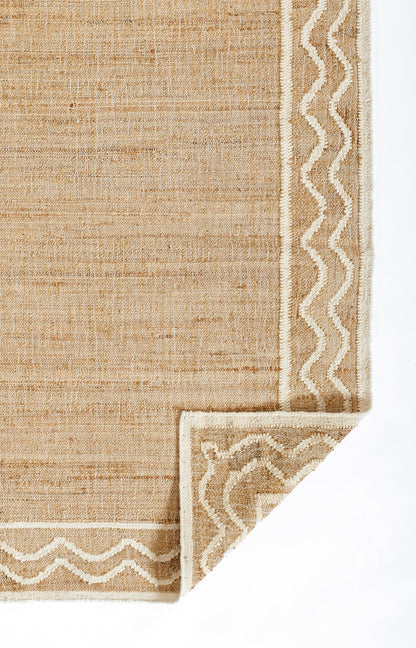 Natural beige woven rug with white zigzag border; rectangular, jute-like texture with a folded corner.