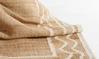 Natural beige woven rug with a white chevron stripe; textured jute-cotton blend, shown folded for display.