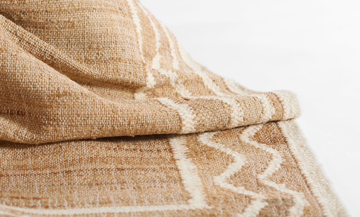 Natural beige woven rug/throw with white chevron stripes; rustic textured fabric, boho style.