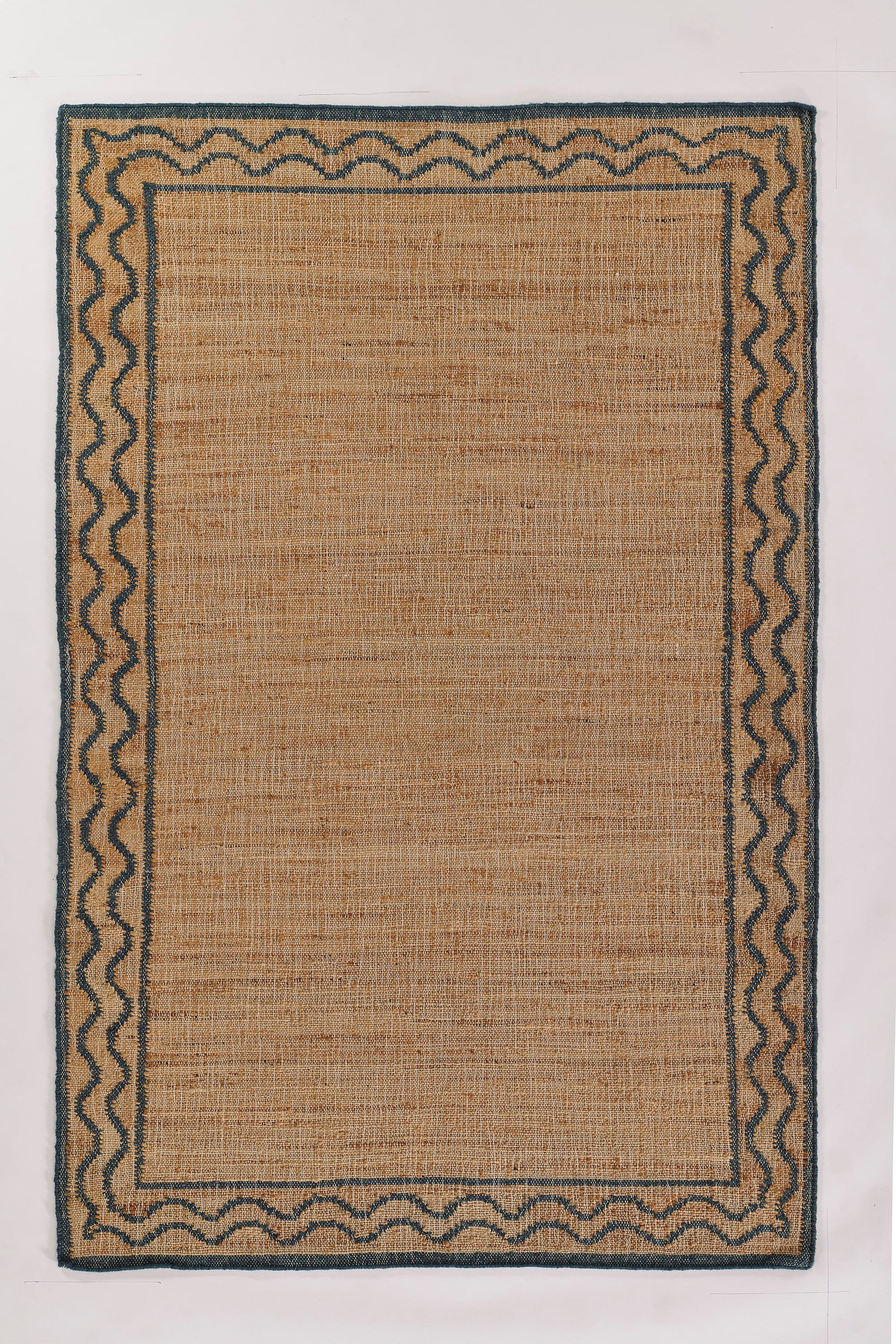 Rectangular natural jute rug with blue zigzag border and dark outer edge; woven, neutral accent for living room.