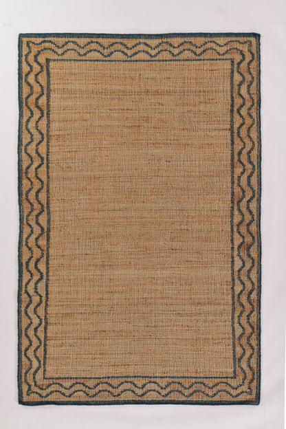 Rectangular natural jute rug with blue zigzag border and dark outer edge; woven, neutral accent for living room.