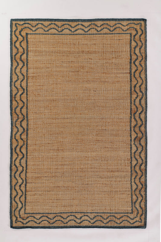 Rectangular natural jute rug with blue zigzag border and dark outer edge; woven, neutral accent for living room.