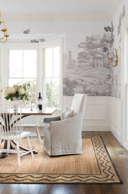 Bright dining room with white chairs, beige slipcovered armchair, glass dining table, wine bottle, 8' x 10' rug, black-and-white mural.