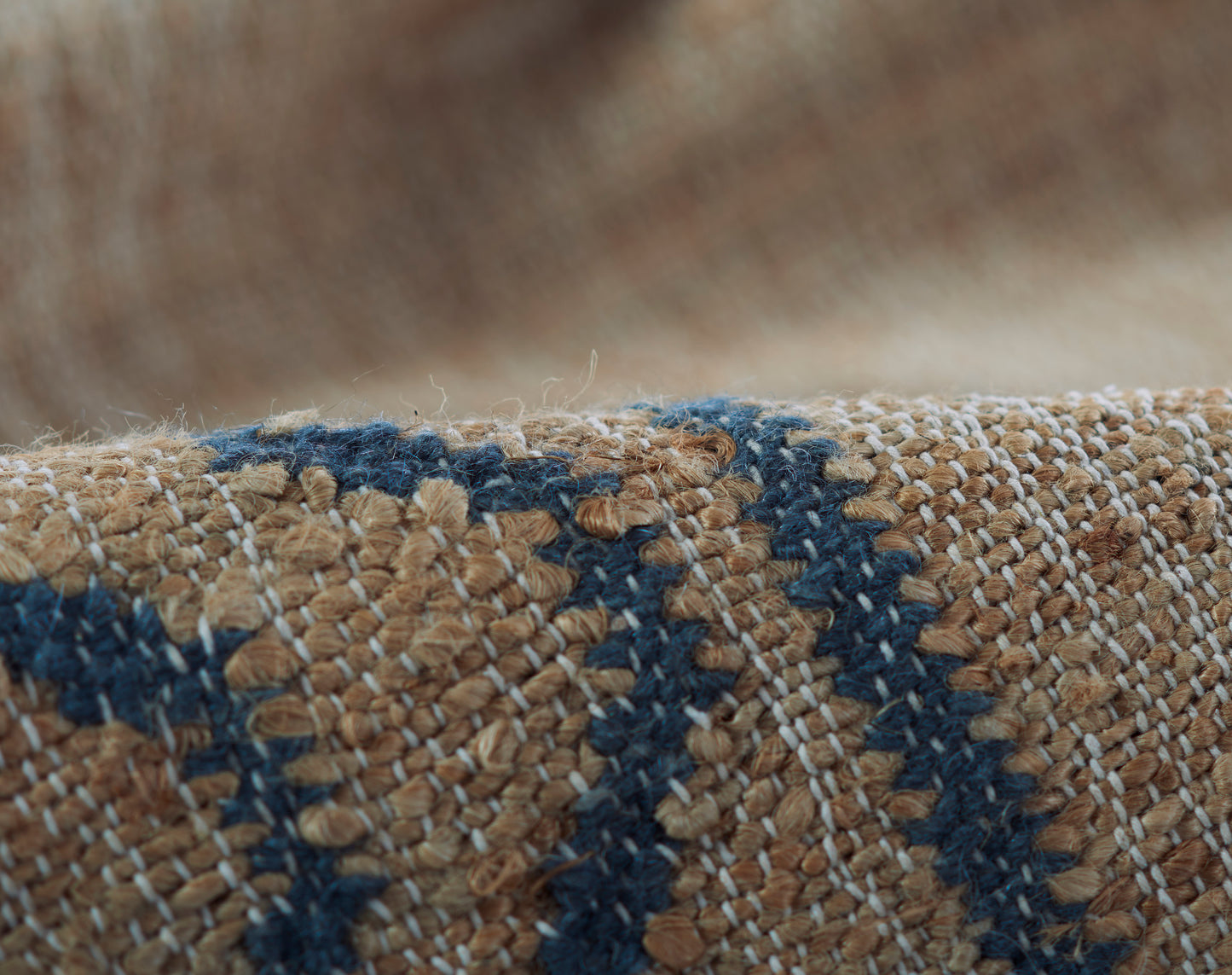 Coarse woven rug texture in tan with navy geometric stripes and boucle yarns.