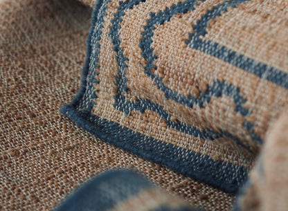 Beige textured woven rug with a dark blue geometric border and navy piping.
