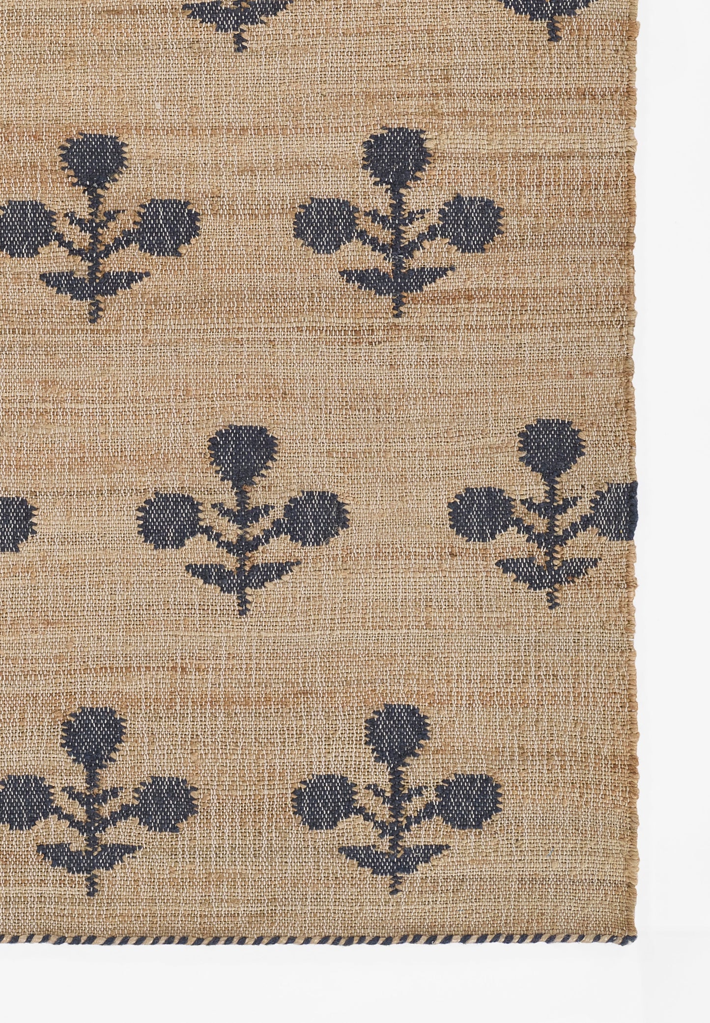 Natural jute runner with navy blue floral motifs; textured weave and casual coastal look.