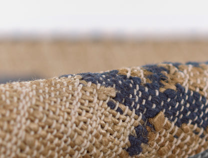 Close-up of a textured, handwoven rug in beige and navy with a geometric stripe pattern.