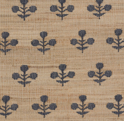 Tan woven rug with navy blue floral cluster pattern repeating across a rustic burlap texture.