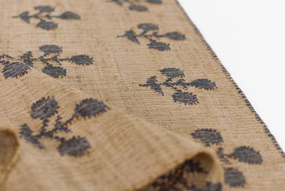 Beige woven textile with dark blue floral clusters, navy border; rectangular scarf or table runner in linen-cotton blend.