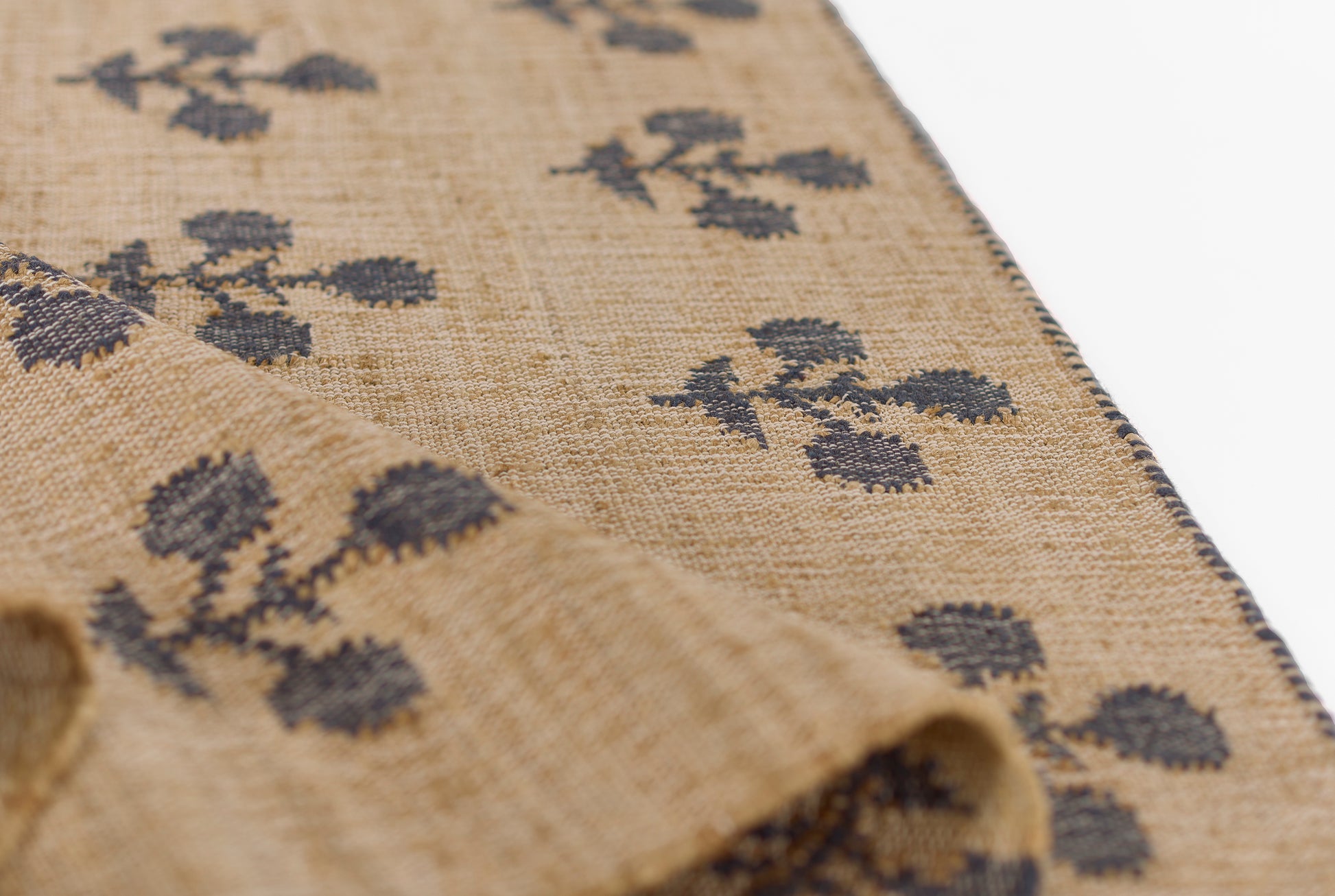 Beige woven textile with navy floral clusters and dark blue bordered edge, scarf or table runner.