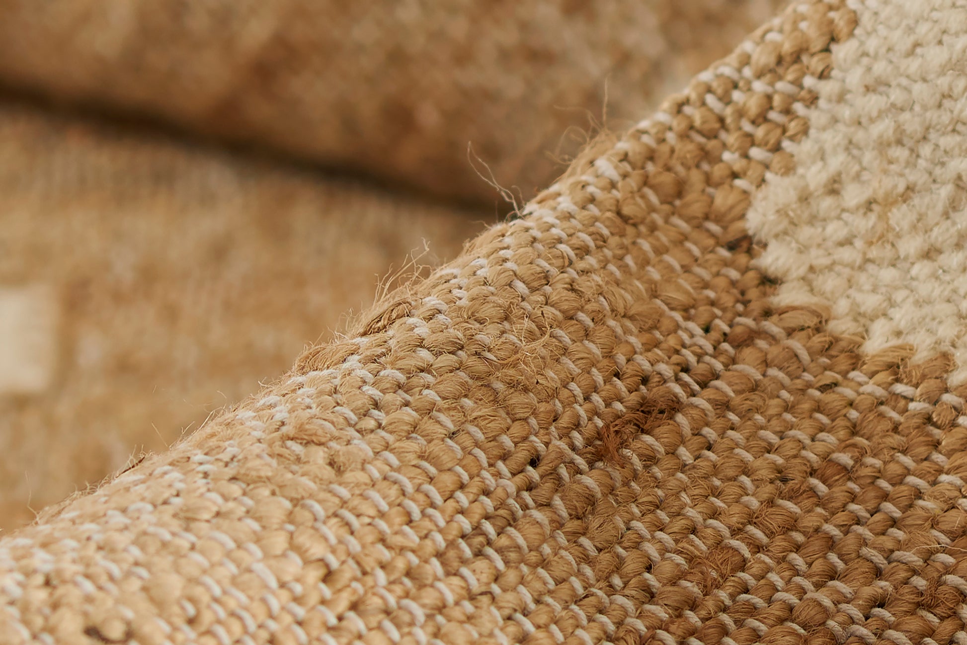 Natural beige woven jute rug close-up with cream accents; chunky textured, rustic style.