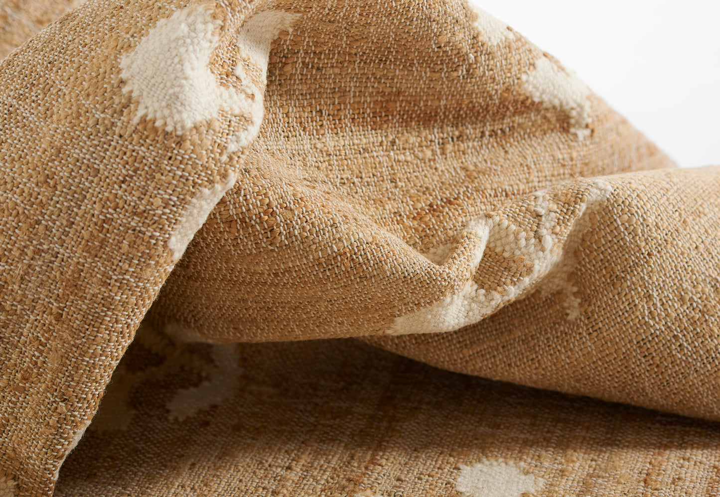 Beige jute-woven rug runner, 2'3" x 8', with cream abstract patterns, textured and folded.