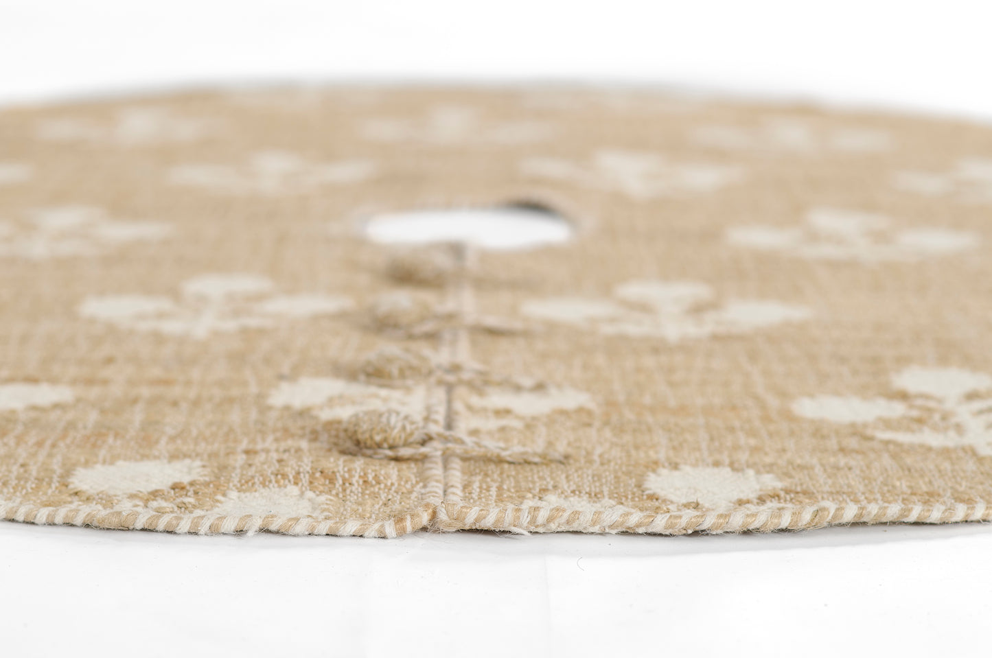 Natural beige jute round rug with white floral motifs and braided edge, 5' diameter.
