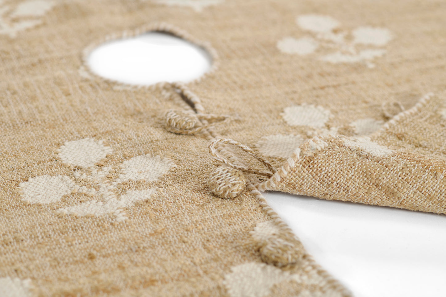 Natural jute round tree skirt with cream polka dots, tassel fringe, and a central hole for the Christmas tree trunk.