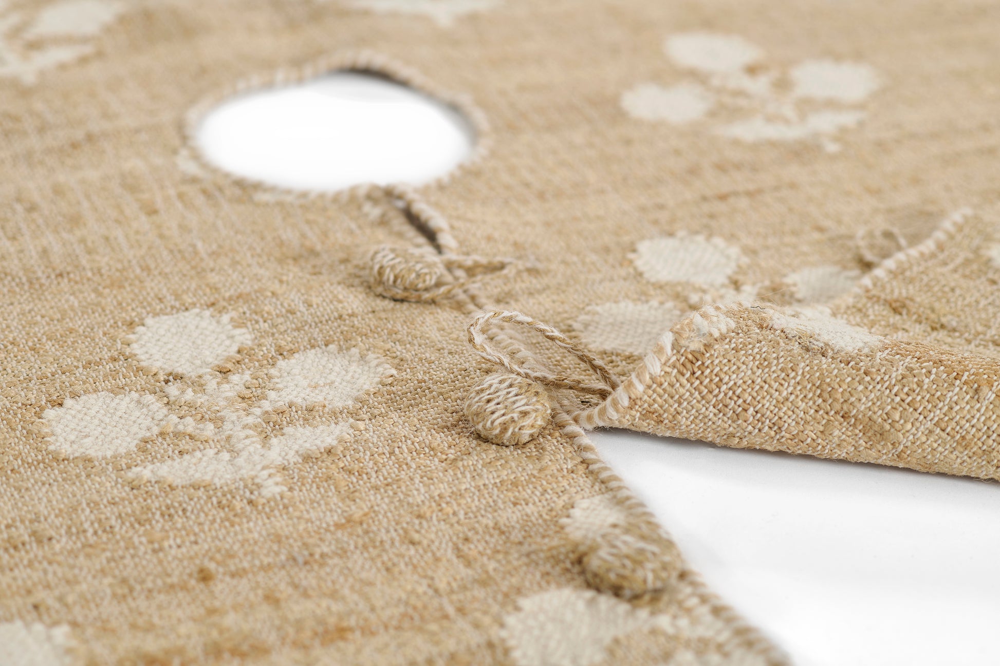 Natural jute round tree skirt with cream polka dots, tassel fringe, and a central hole for the Christmas tree trunk.