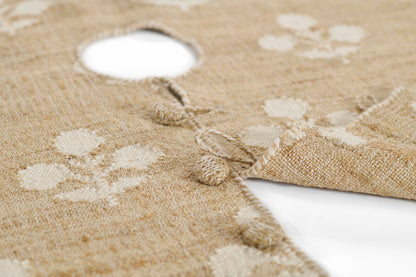Natural jute round tree skirt with cream polka dots, tassel fringe, and a central hole for the Christmas tree trunk.