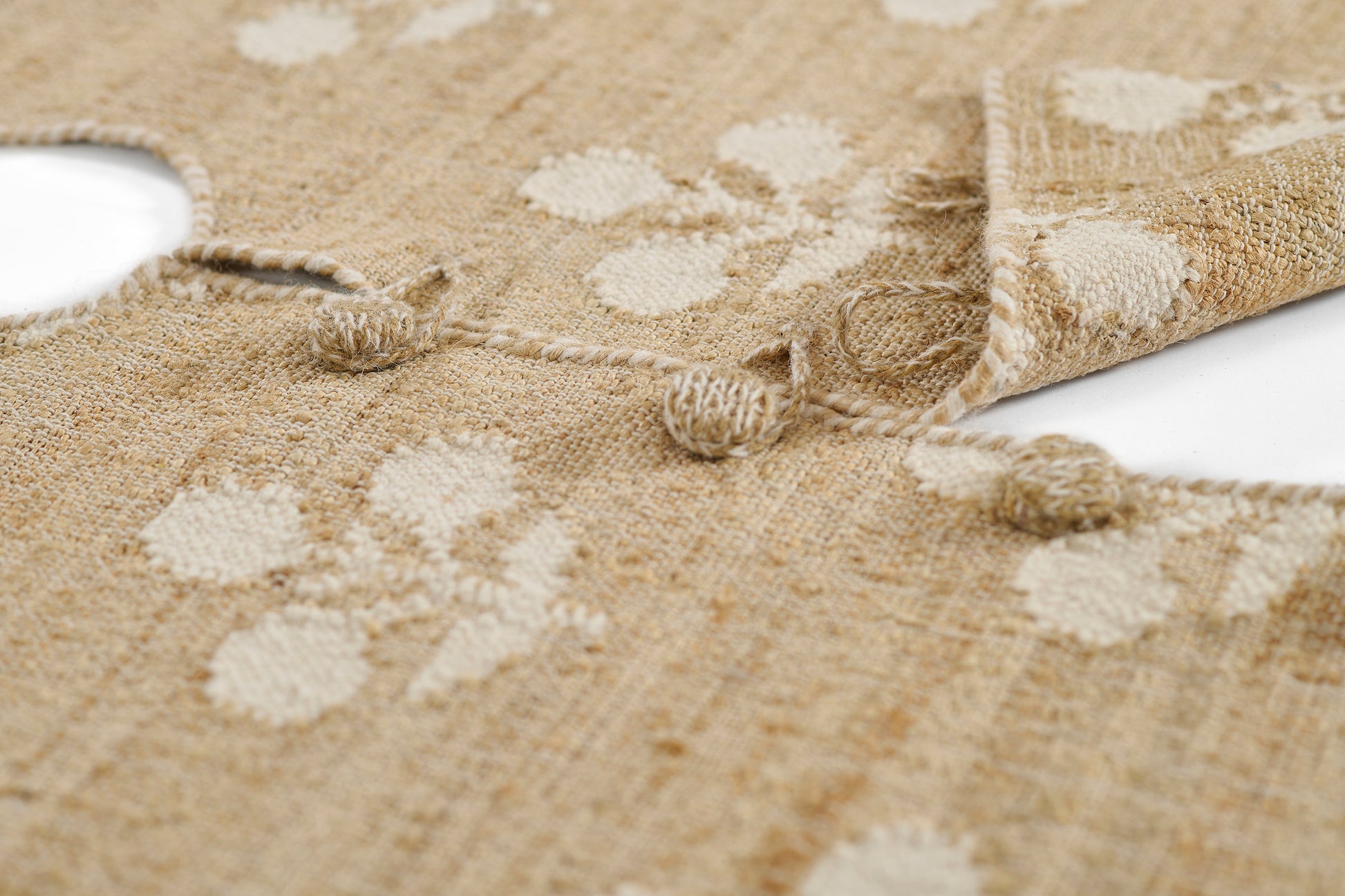 Natural beige circular rug with white spots, woven jute texture, knotted fringe edge, 5' round.