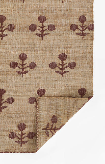 Beige jute rug with brown floral motifs, natural rustic design; folded corner visible.