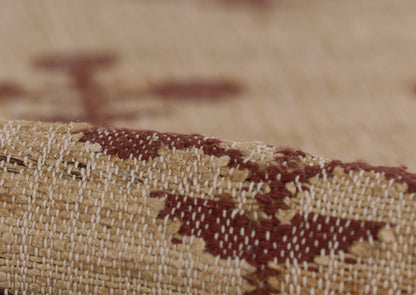 Close-up of a beige woven rug with dark maroon geometric pattern and visible textured fibers.