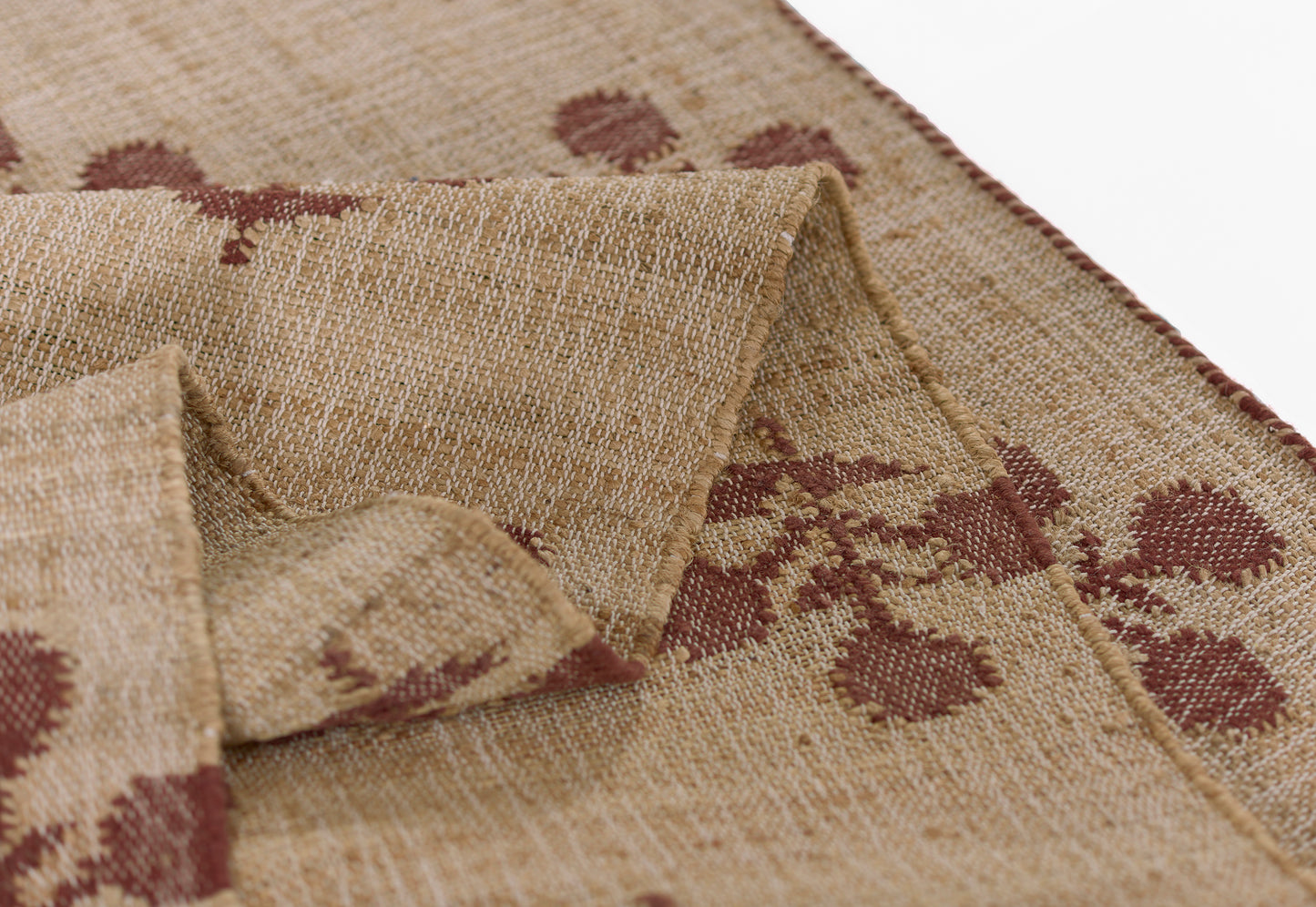 Natural beige jute rug with maroon botanical motifs and a coarse woven texture.