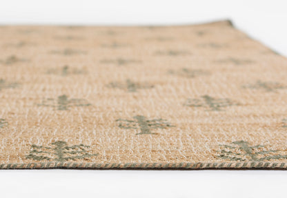 Natural beige woven rug with subtle green geometric motifs and braided green edge, close-up view.