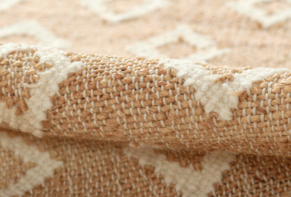 Close-up of natural beige jute rug with white geometric motif and chunky woven texture.