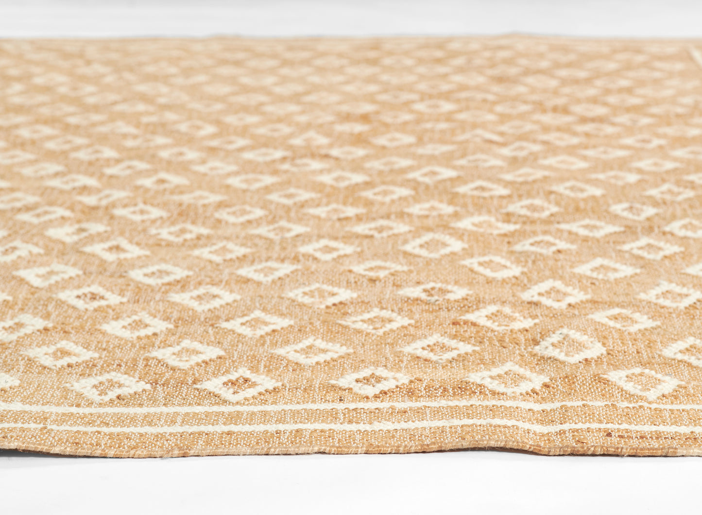 Natural jute rug with white diamond geometric pattern on tan background; rectangular, boho coastal style.