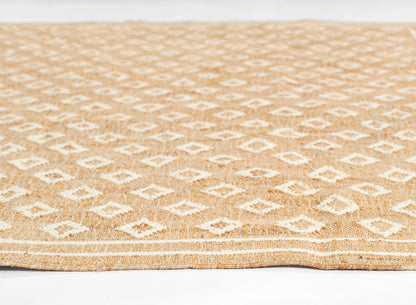 Natural jute rug with white diamond geometric pattern on tan background; rectangular, boho coastal style.