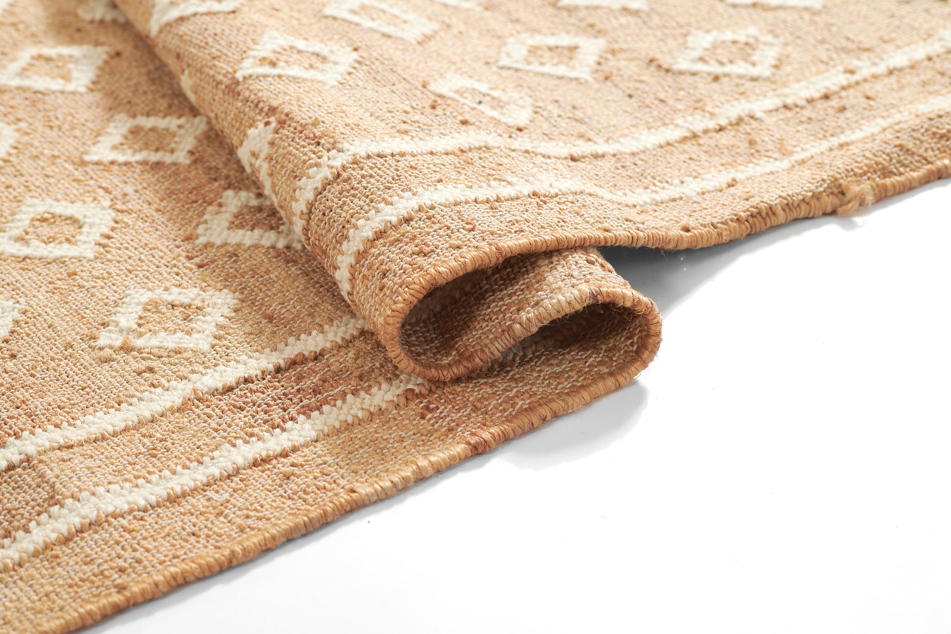 Natural beige rug with cream geometric diamond pattern and soft looped pile, partially rolled.